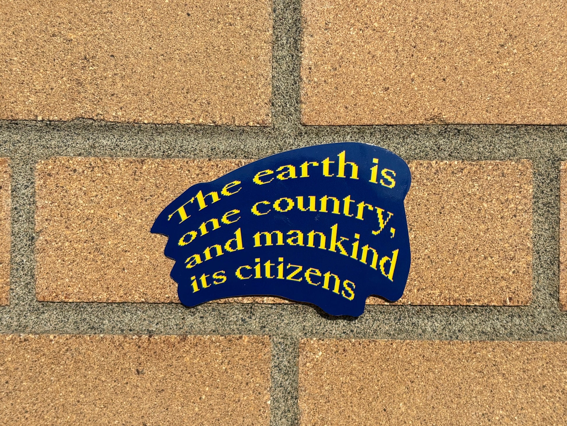 Yellow and blue sticker on a brick wall