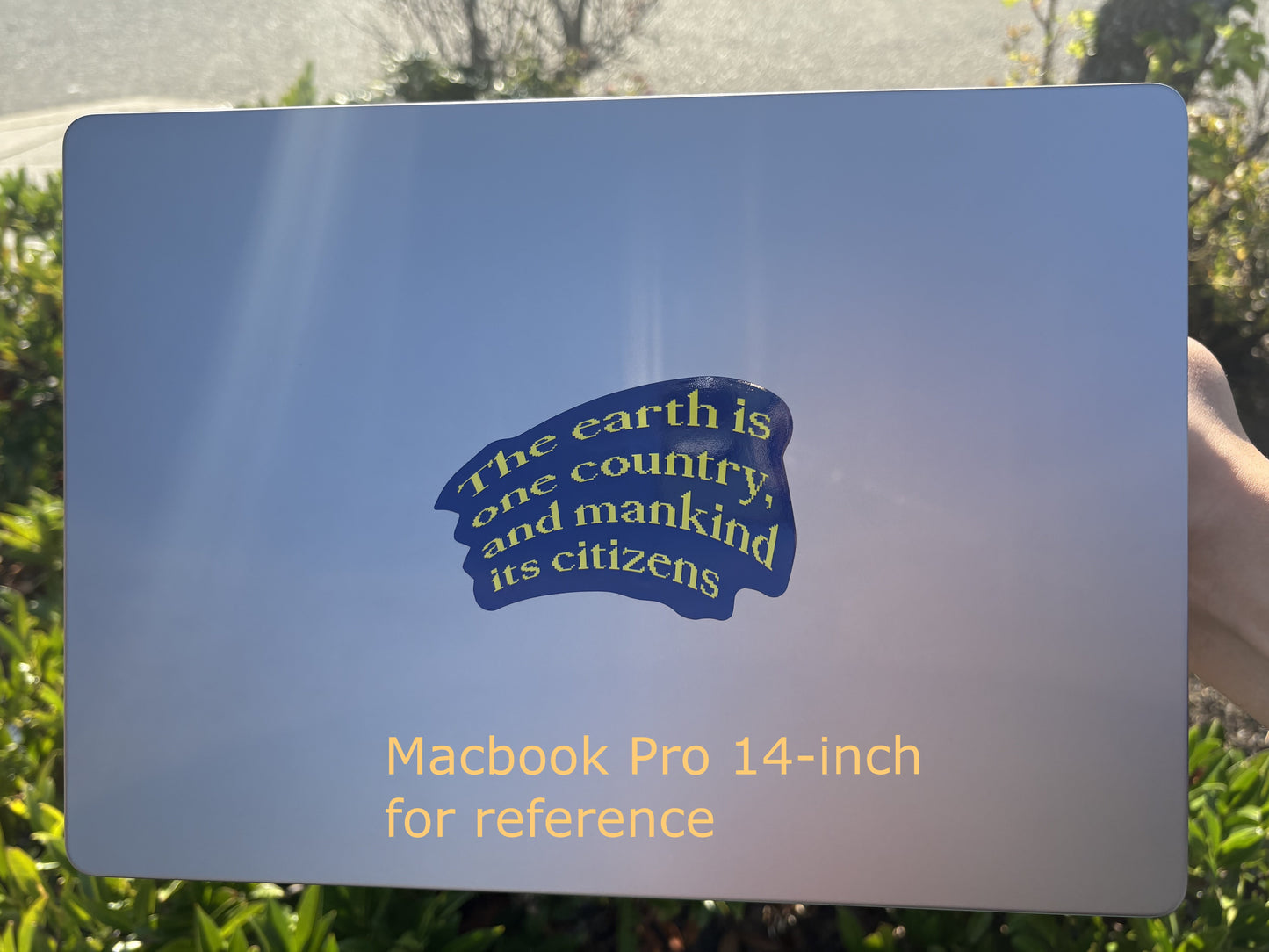 Macbook Pro 14-inch with a blue sticker on a grassy background